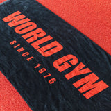 Black towel with 'World Gym' text on a red surface